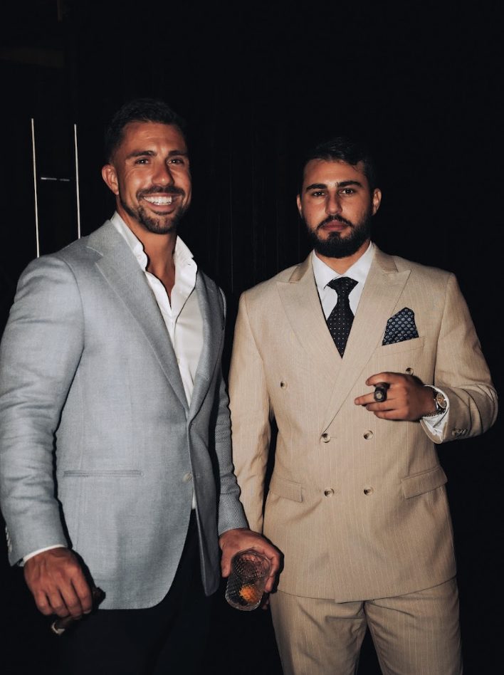 Two members in tailored suits at an evening event
